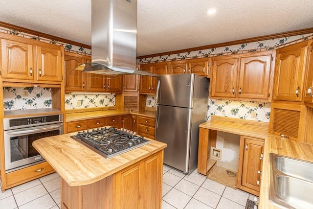 kitchen featuring stainless steel appliances, butcher block countertops, a textured ceiling, island range hood, and a kitchen island