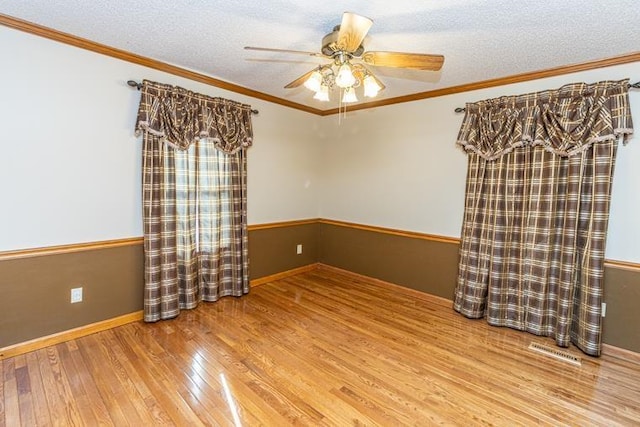 empty room featuring wood-type flooring, a textured ceiling, ceiling fan, and ornamental molding