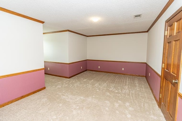 unfurnished room with a textured ceiling, light colored carpet, and crown molding