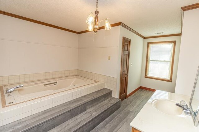 bathroom featuring an inviting chandelier, a relaxing tiled tub, crown molding, a textured ceiling, and hardwood / wood-style flooring