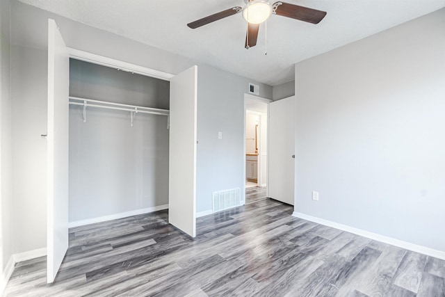 unfurnished bedroom featuring hardwood / wood-style floors, a closet, and ceiling fan