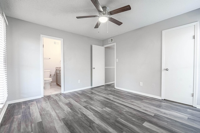 unfurnished bedroom featuring a textured ceiling, hardwood / wood-style flooring, ensuite bath, and ceiling fan