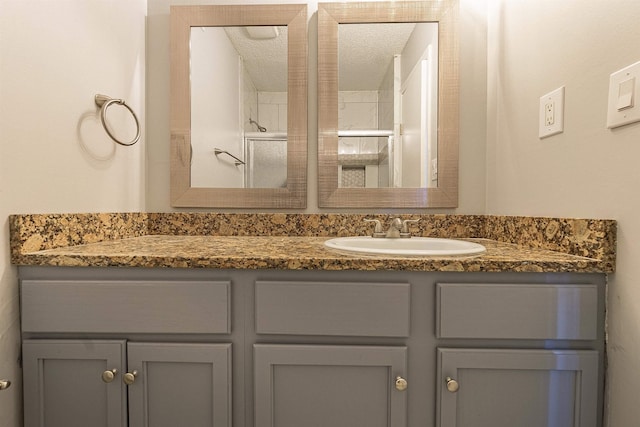 bathroom featuring vanity, a shower with shower door, and a textured ceiling