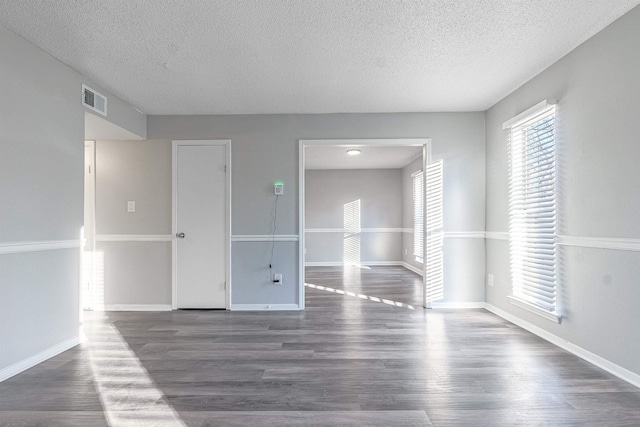 empty room featuring a textured ceiling and dark hardwood / wood-style floors