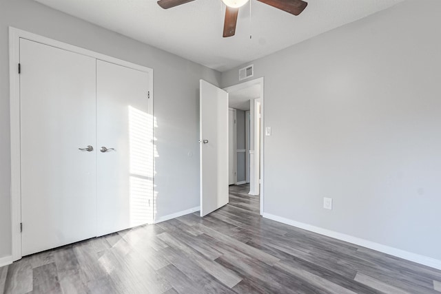 unfurnished bedroom featuring hardwood / wood-style flooring, ceiling fan, and a closet