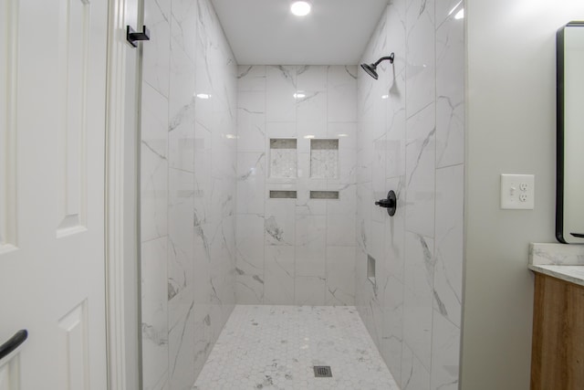 bathroom with vanity and a tile shower