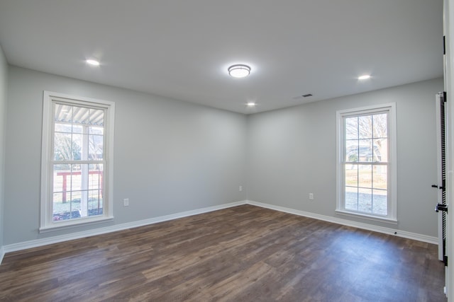 empty room with a healthy amount of sunlight and dark hardwood / wood-style flooring