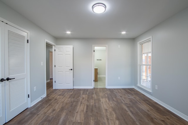 unfurnished bedroom featuring connected bathroom and dark wood-type flooring