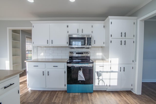 kitchen with crown molding, hardwood / wood-style flooring, appliances with stainless steel finishes, tasteful backsplash, and white cabinetry