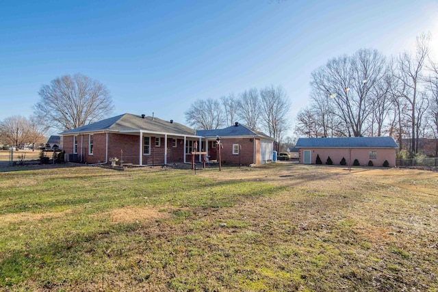 rear view of property featuring a yard and an outbuilding