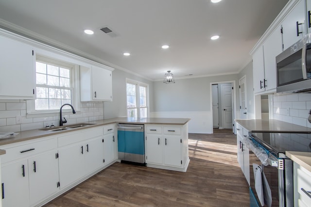 kitchen with dark wood-type flooring, white cabinets, sink, appliances with stainless steel finishes, and kitchen peninsula