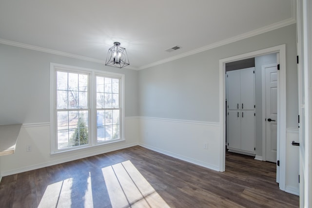 spare room featuring dark hardwood / wood-style flooring, crown molding, and an inviting chandelier