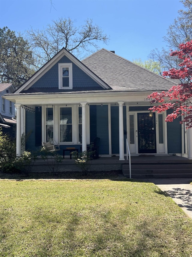 rear view of house featuring a porch and a lawn