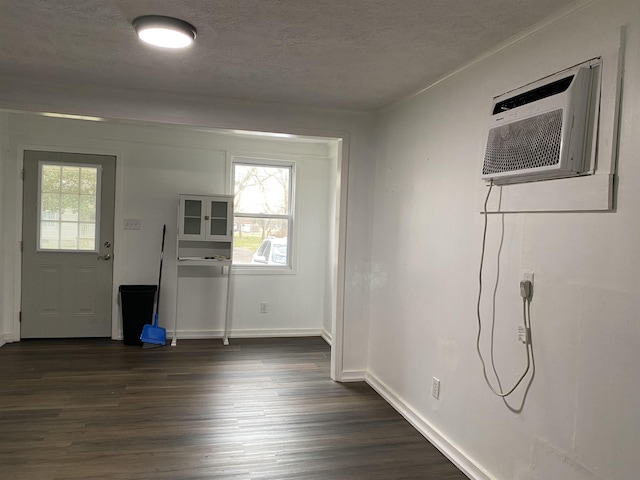 entryway with a wall unit AC, dark hardwood / wood-style flooring, and a textured ceiling