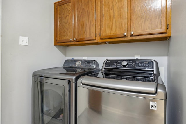 washroom with washing machine and clothes dryer and cabinets