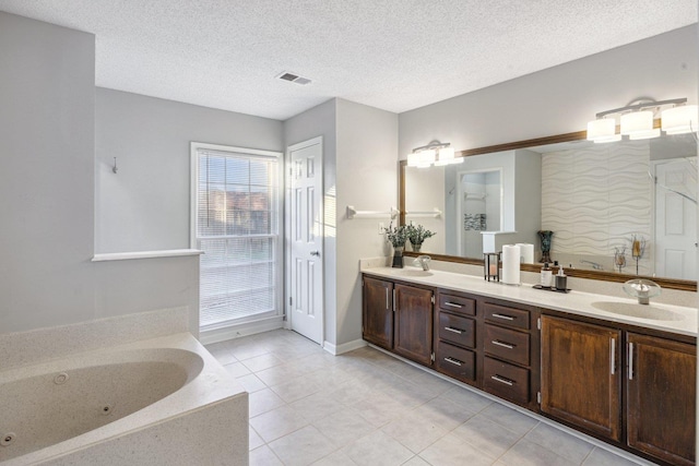 bathroom with a bathing tub, vanity, a textured ceiling, and tile patterned flooring