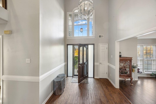 entrance foyer with a towering ceiling, dark wood-type flooring, and a notable chandelier