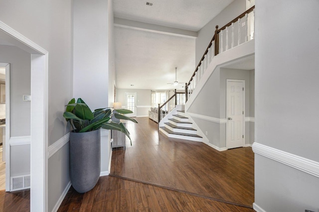 foyer entrance with ceiling fan and dark wood-type flooring