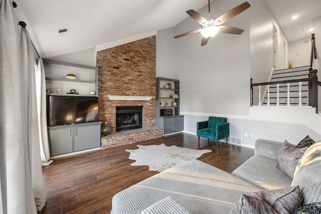 living room featuring a brick fireplace, a textured ceiling, ceiling fan, high vaulted ceiling, and dark hardwood / wood-style floors