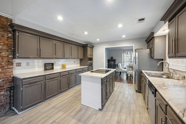 kitchen featuring tasteful backsplash, sink, light hardwood / wood-style flooring, and appliances with stainless steel finishes