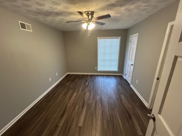 unfurnished room with a textured ceiling, ceiling fan, and dark wood-type flooring