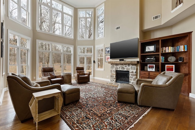 living room featuring a fireplace, hardwood / wood-style floors, and a high ceiling