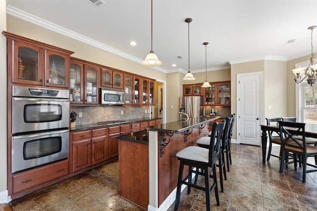 kitchen with appliances with stainless steel finishes, backsplash, decorative light fixtures, and an island with sink