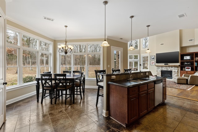 kitchen with dishwasher, sink, decorative light fixtures, a healthy amount of sunlight, and a kitchen bar