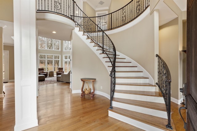 entryway featuring light wood-type flooring, a towering ceiling, and crown molding