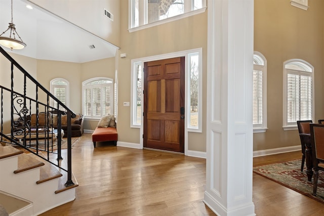 entryway featuring wood-type flooring, a high ceiling, and decorative columns