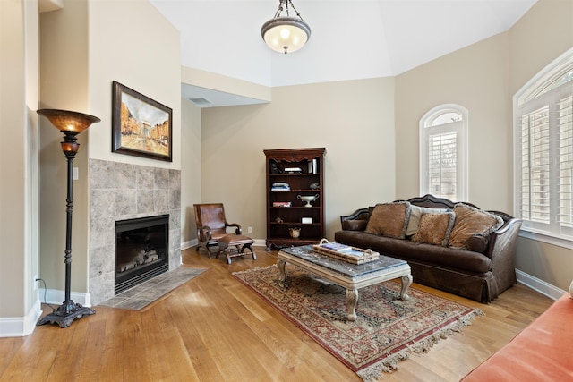 living room featuring a tile fireplace, hardwood / wood-style flooring, a wealth of natural light, and lofted ceiling