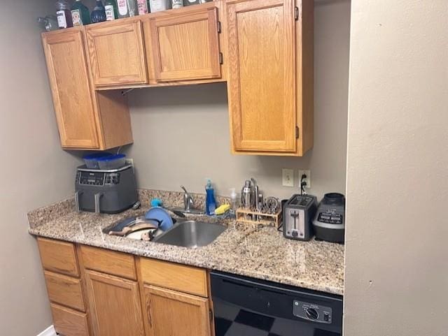 kitchen with light stone counters, sink, and black dishwasher