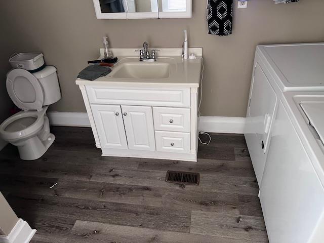 bathroom featuring vanity, toilet, wood-type flooring, and washer / clothes dryer