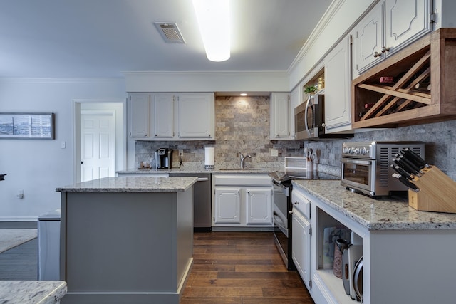 kitchen with decorative backsplash, appliances with stainless steel finishes, white cabinetry, and light stone countertops