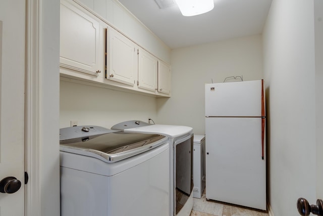 clothes washing area featuring cabinets and washing machine and dryer