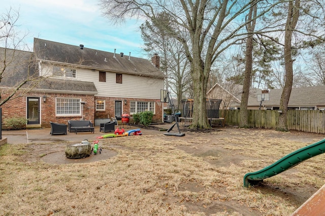 rear view of house featuring a trampoline, a playground, a patio, and an outdoor living space with a fire pit