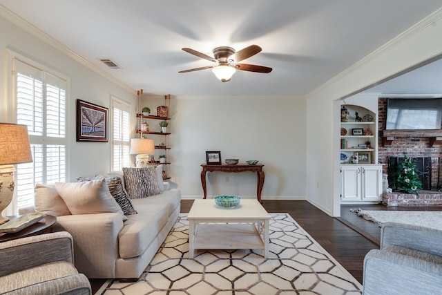 living room featuring hardwood / wood-style floors, crown molding, ceiling fan, built in features, and a fireplace