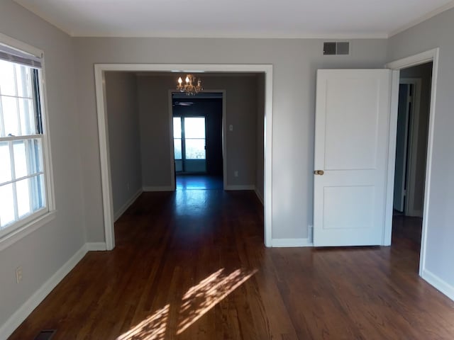 hall featuring a healthy amount of sunlight, dark hardwood / wood-style flooring, and a chandelier