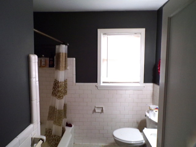 bathroom featuring shower / bath combination with curtain, toilet, and tile walls