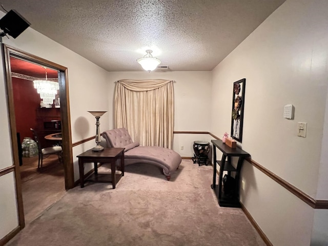 sitting room with carpet floors, a textured ceiling, and a chandelier