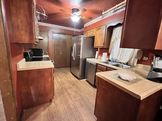 kitchen featuring sink, stainless steel appliances, a textured ceiling, and light wood-type flooring