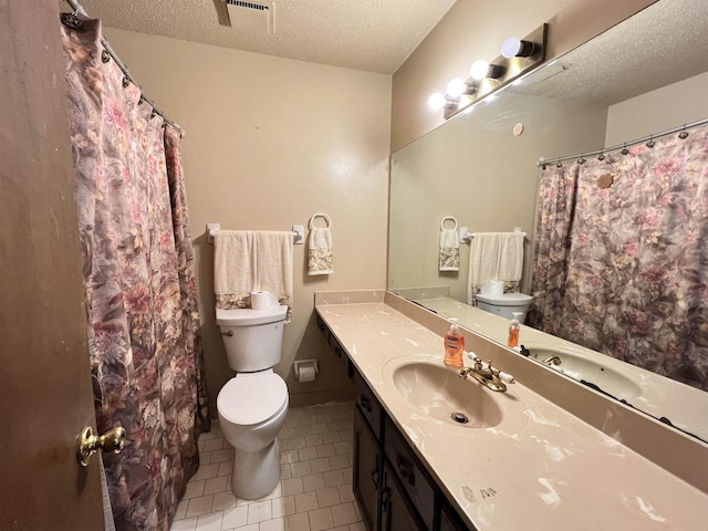 bathroom with tile patterned flooring, vanity, a textured ceiling, and toilet