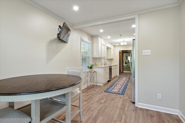 kitchen featuring crown molding, light hardwood / wood-style floors, decorative backsplash, white cabinets, and appliances with stainless steel finishes