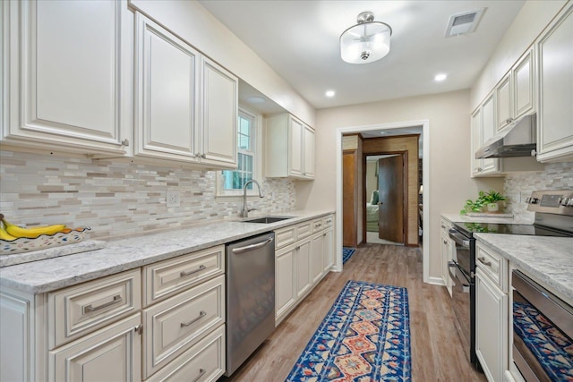 kitchen featuring appliances with stainless steel finishes, light stone counters, white cabinetry, and sink