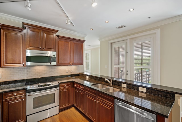 kitchen with stainless steel appliances, dark stone countertops, and sink