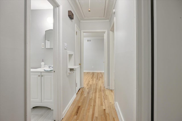 corridor featuring light hardwood / wood-style flooring, crown molding, and sink