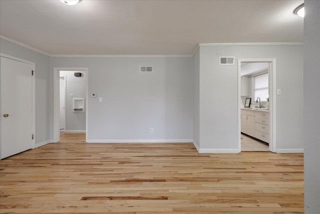 empty room with crown molding, sink, and light hardwood / wood-style flooring