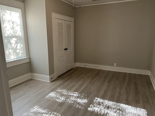 unfurnished bedroom featuring light wood-type flooring, ornamental molding, and a closet