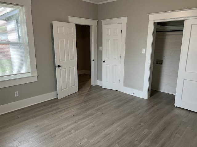 unfurnished bedroom with crown molding and dark wood-type flooring