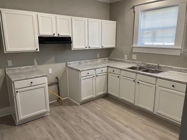 kitchen featuring light wood-type flooring, white cabinetry, and sink